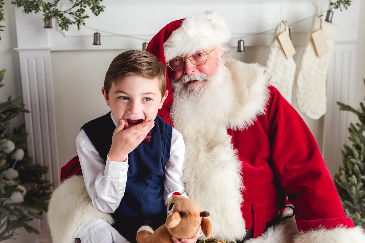 A little boy excited to meet santa. He is sitting in santa's lap during a holiday mini session at Kelli Dease Photography in Farmington, CT.