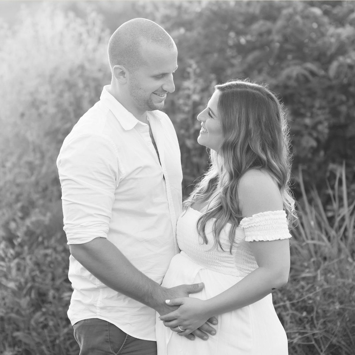 Black and white photo of a couple embracing outdoors during a maternity session at Kelli Dease Photography, Farmington, CT