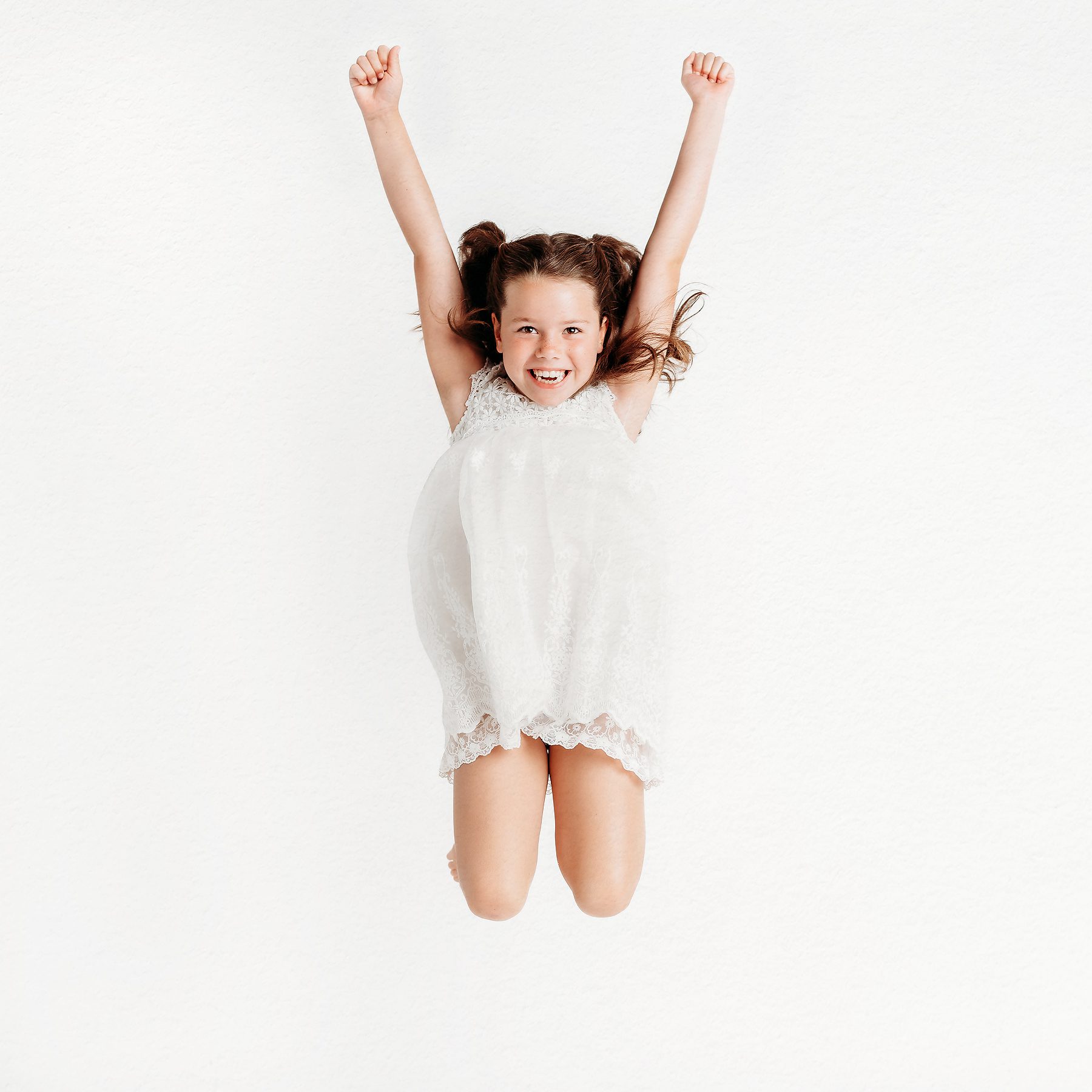 Young girl jumping with arms raised and a huge smile, studio children's portrait in Connecticut