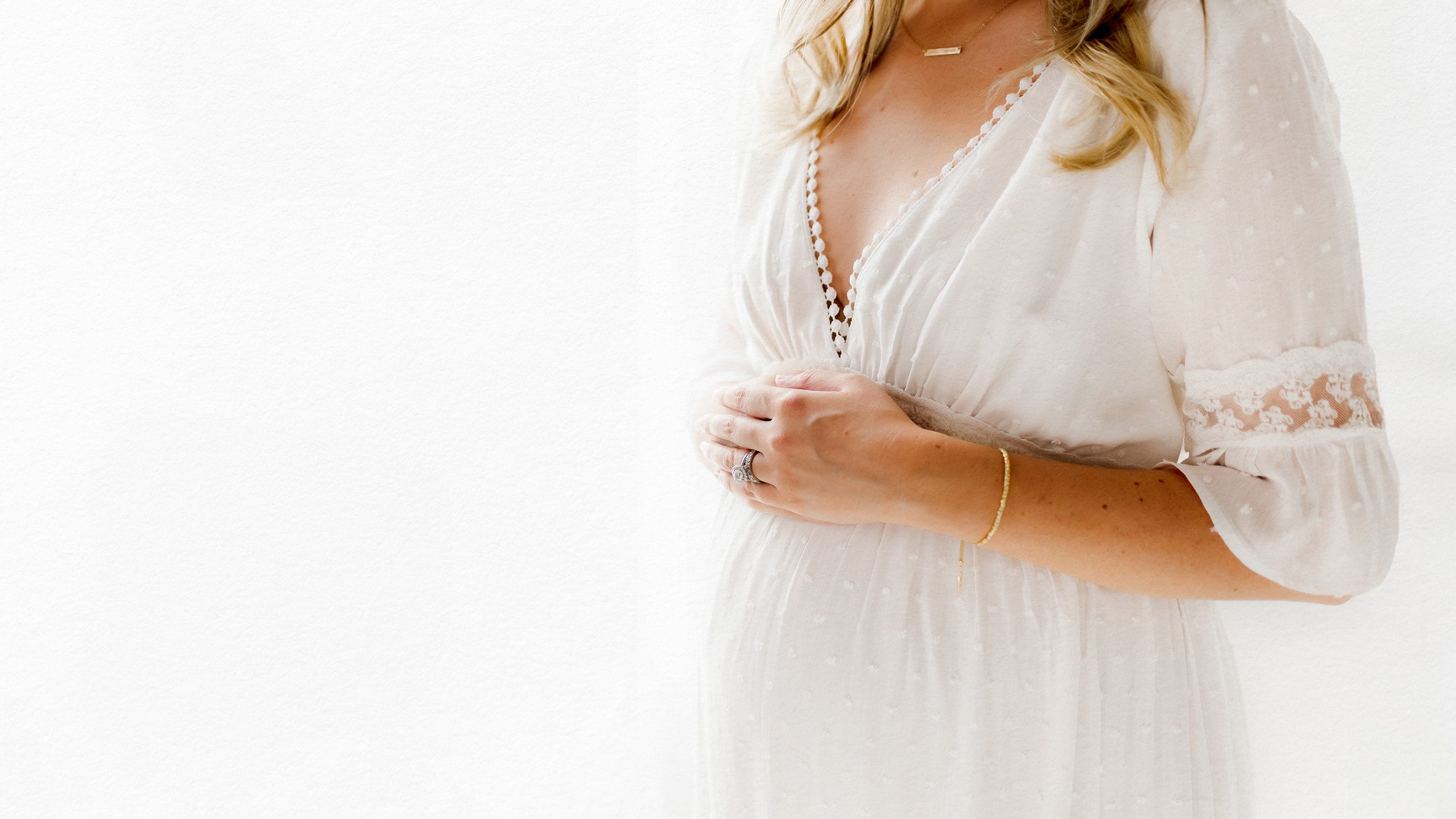Studio maternity detail photo showing bump. Minimalistic style with white background.