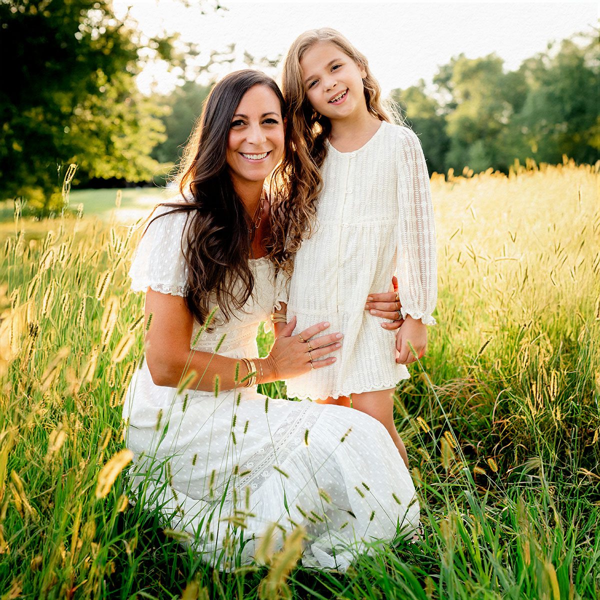 Outdoor family photo session in Simsbury, CT captured in a soft, minimalistic style, highlighting genuine smiles and natural poses in a scenic field.