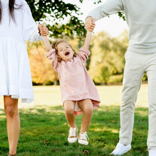 Outdoor family photo session in Simsbury, CT captured in a soft, minimalistic style, highlighting genuine smiles and natural poses in a scenic field.