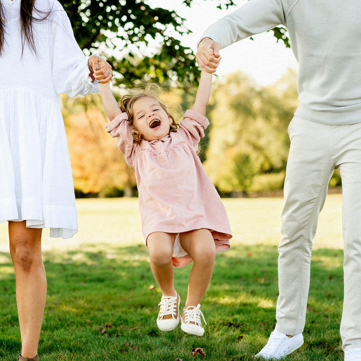 Young girl in pink dress being lifted by parent in a Connecticut field, Kelli Dease Photography
