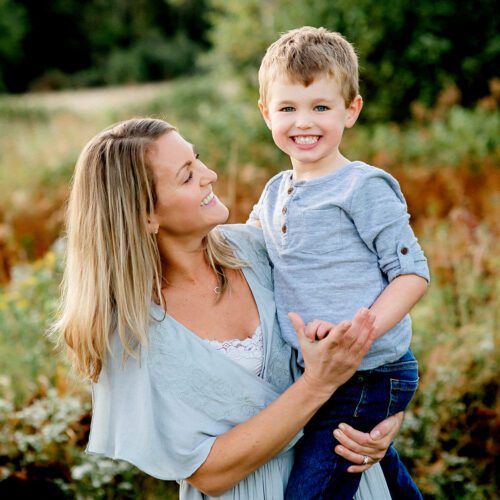 Outdoor family photo session in Simsbury, CT captured in a soft, minimalistic style, highlighting genuine smiles and natural poses in a scenic field.