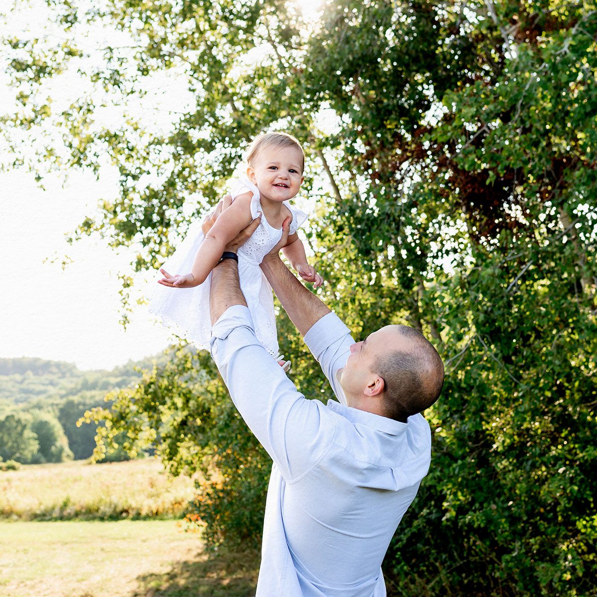 Outdoor family photo session in Simsbury, CT captured in a soft, minimalistic style, highlighting genuine smiles and natural poses in a scenic field.