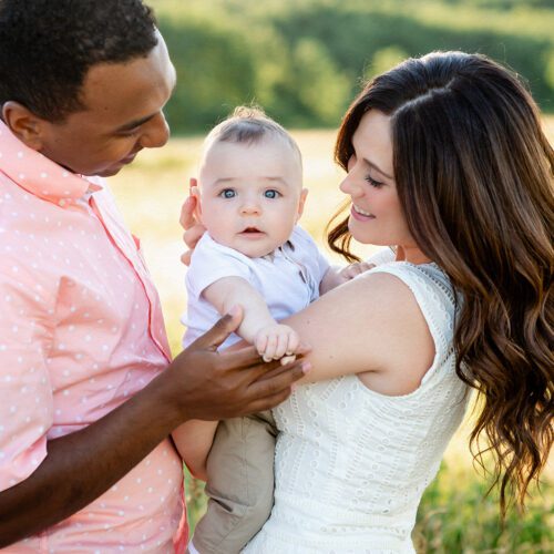 Outdoor family photo session in Simsbury, CT captured in a soft, minimalistic style, highlighting genuine smiles and natural poses in a scenic field.