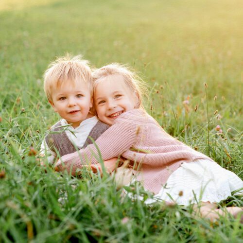 Outdoor family photo session in Simsbury, CT captured in a soft, minimalistic style, highlighting genuine smiles and natural poses in a scenic field.