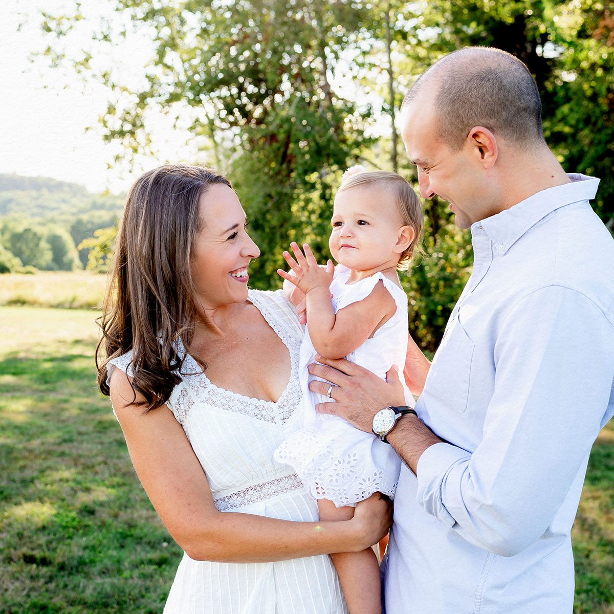 Outdoor family photo session in Simsbury, CT captured in a soft, minimalistic style, highlighting genuine smiles and natural poses in a scenic field.