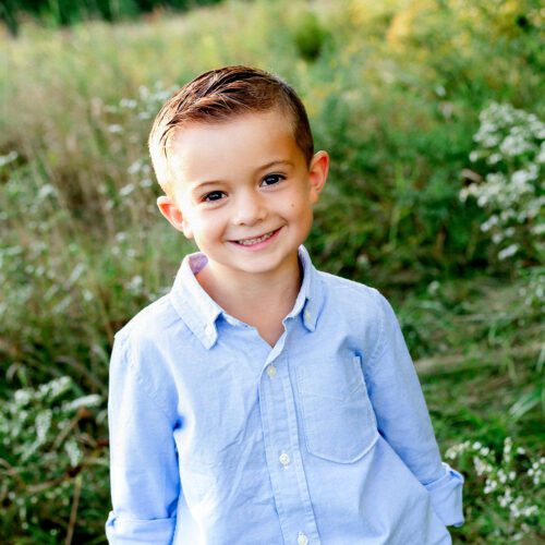 Outdoor family photo session in Simsbury, CT captured in a soft, minimalistic style, highlighting genuine smiles and natural poses in a scenic field.