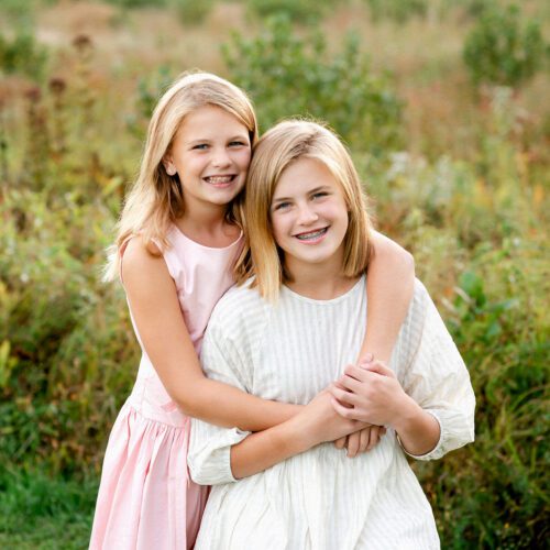 Outdoor family photo session in Simsbury, CT captured in a soft, minimalistic style, highlighting genuine smiles and natural poses in a scenic field.