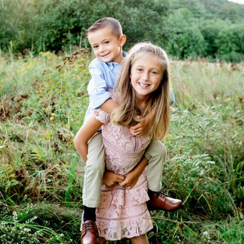 Outdoor family photo session in Simsbury, CT captured in a soft, minimalistic style, highlighting genuine smiles and natural poses in a scenic field.