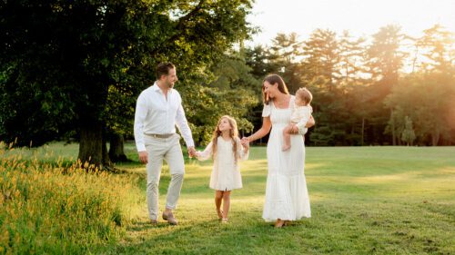 Outdoor family photo session by Farmington, CT family photographer Kelli Dease, captured in a soft, minimalistic style, highlighting genuine smiles and natural poses in a scenic field.