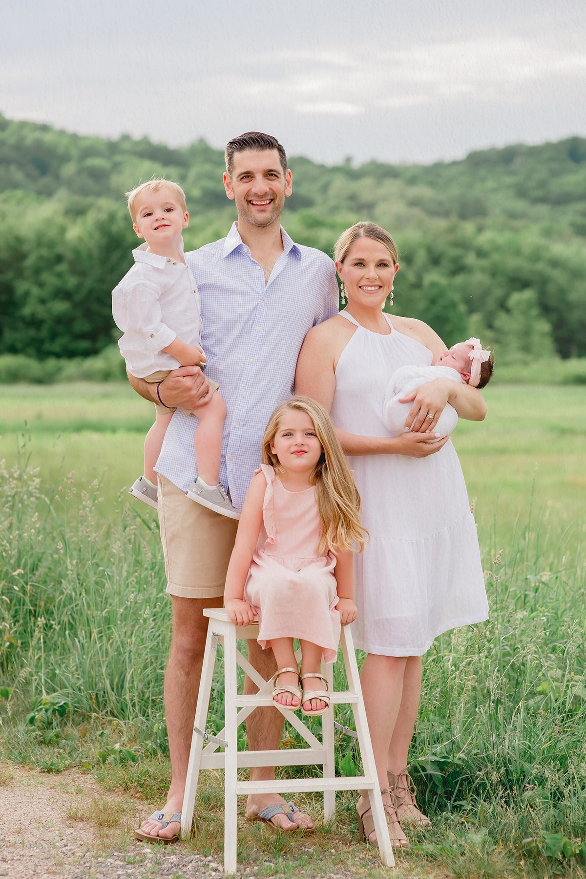 Outdoor Family Photoshoot with Newborn Baby and siblings 2 Sunset family photo session in a golden field featuring a blended family with a newborn and two siblings, showcasing natural connection and relaxed outdoor styling.