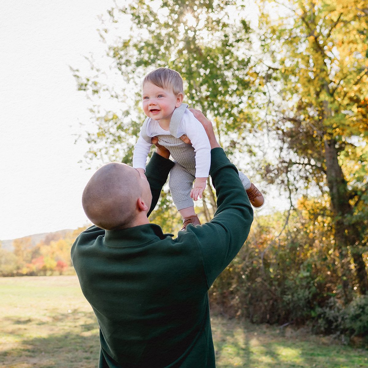 Fall family photoshoot in Simsbury CT featuring a father playing with a toddler in a colorful autumn field.