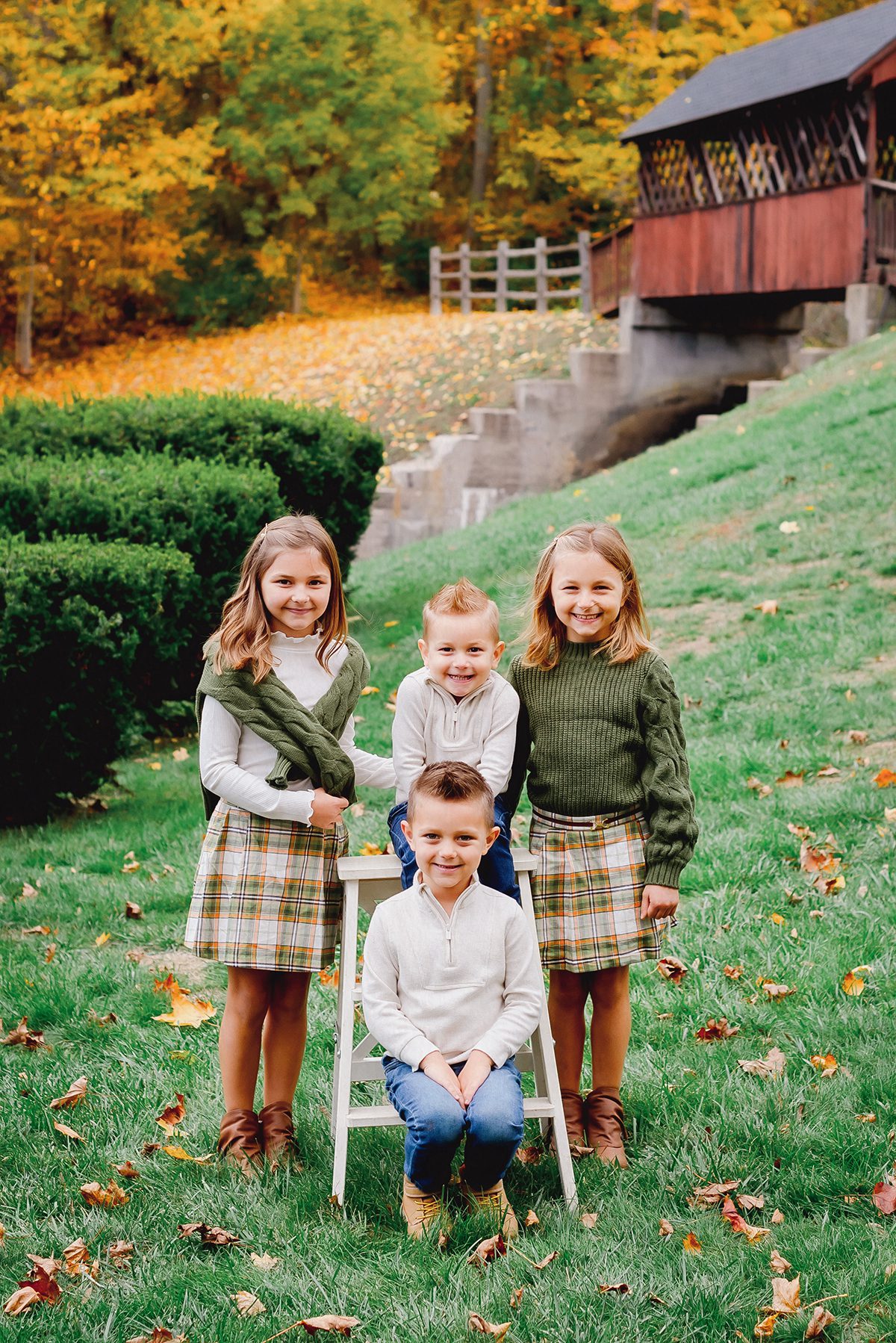 A fall family photoshoot featuring four siblings photographed in front of a covered bridge in Avon, CT.