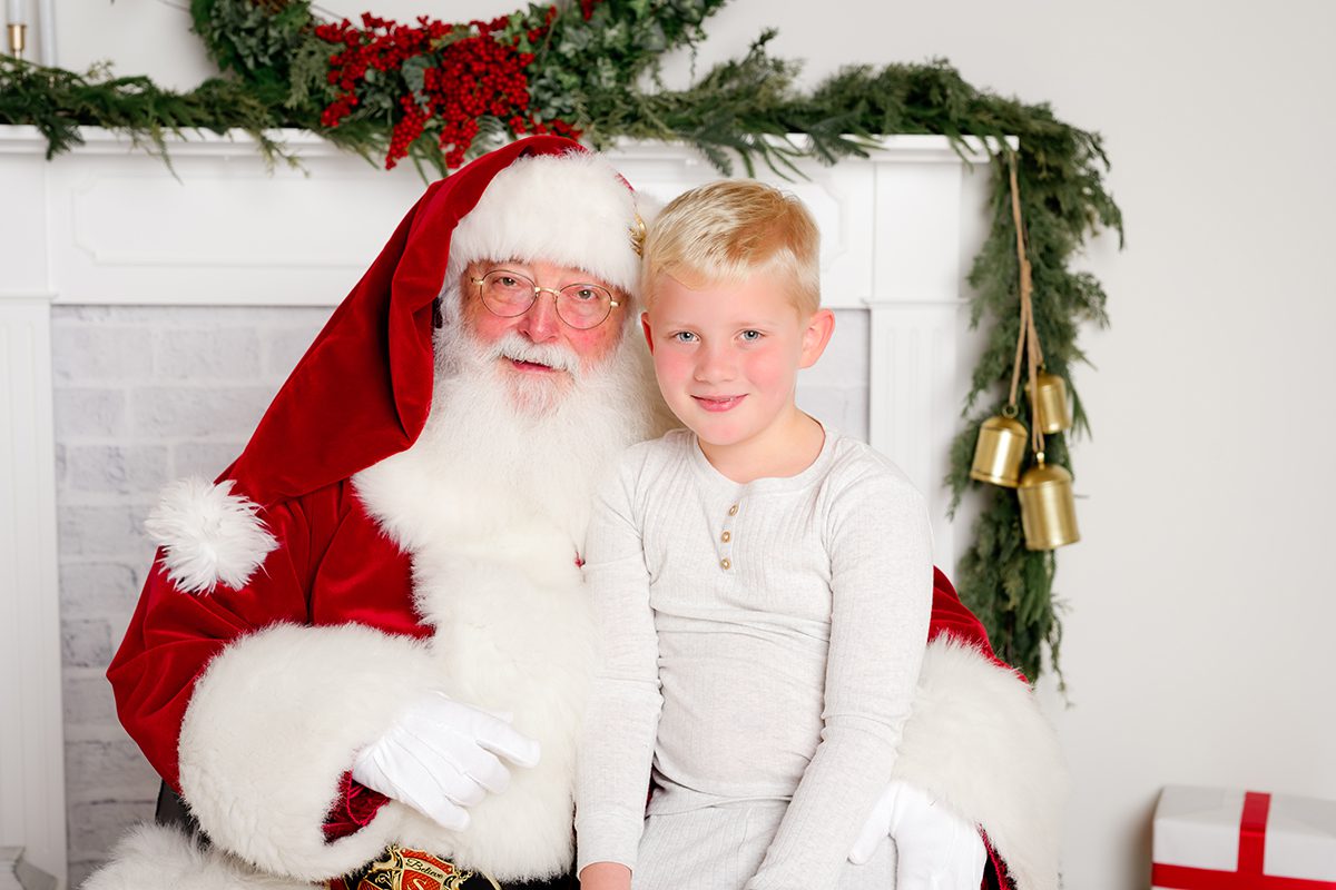 Child sitting on Santa’s lap, smiling while chatting during a studio Santa session.