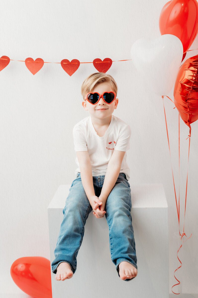 KIDS_VALENTINE_PHOTOS_03 Playful Valentine’s Day portrait of a 4 year old boy with heart decorations and simple styling