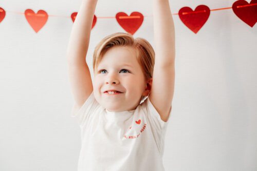 KIDS_VALENTINE_PHOTOS_10 Valentine mini session portrait of a 4 year old boy surrounded by red heart balloons in a bright Connecticut studio