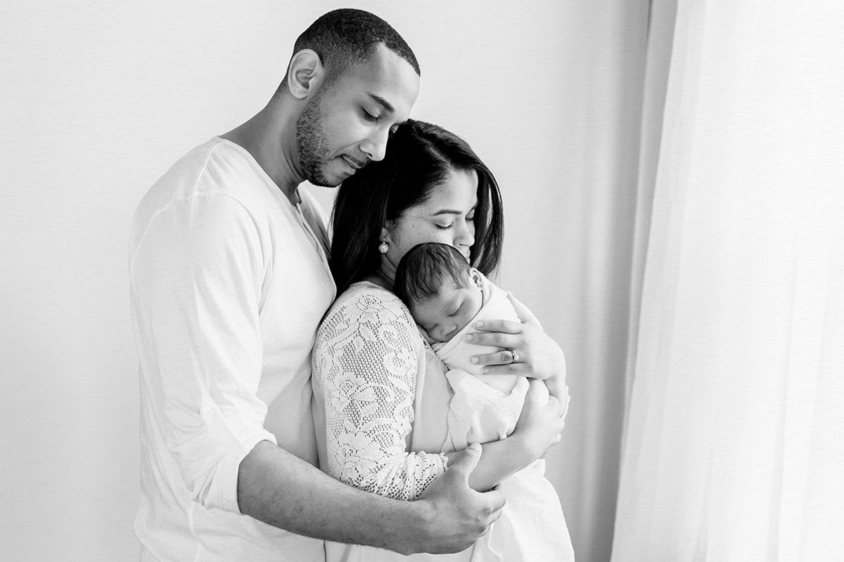 Black and white studio portrait of parents holding their newborn baby, photographed by a Farmington, Connecticut newborn photographer.