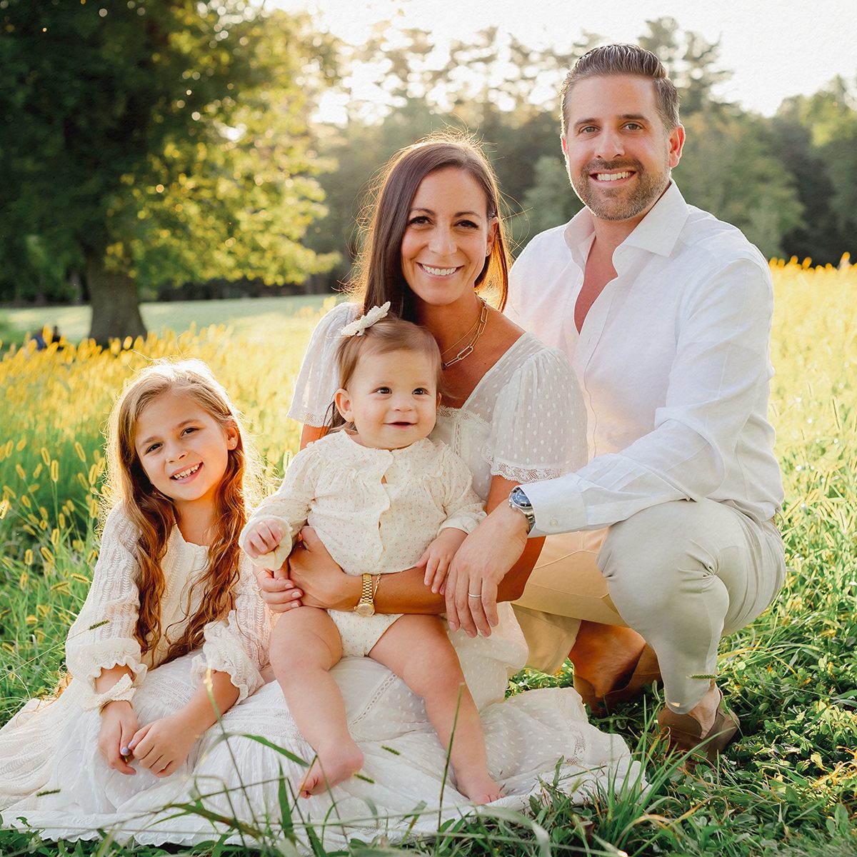 a family in a sunlit field during golden hour, captured during an outdoor family photography session in Connecticut.