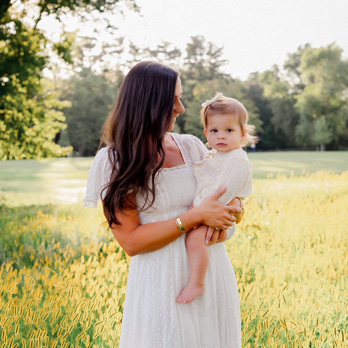 first year package 3 one year image Mother holding her baby girl in a sunlit field during golden hour, captured during an outdoor family photography session in Connecticut.