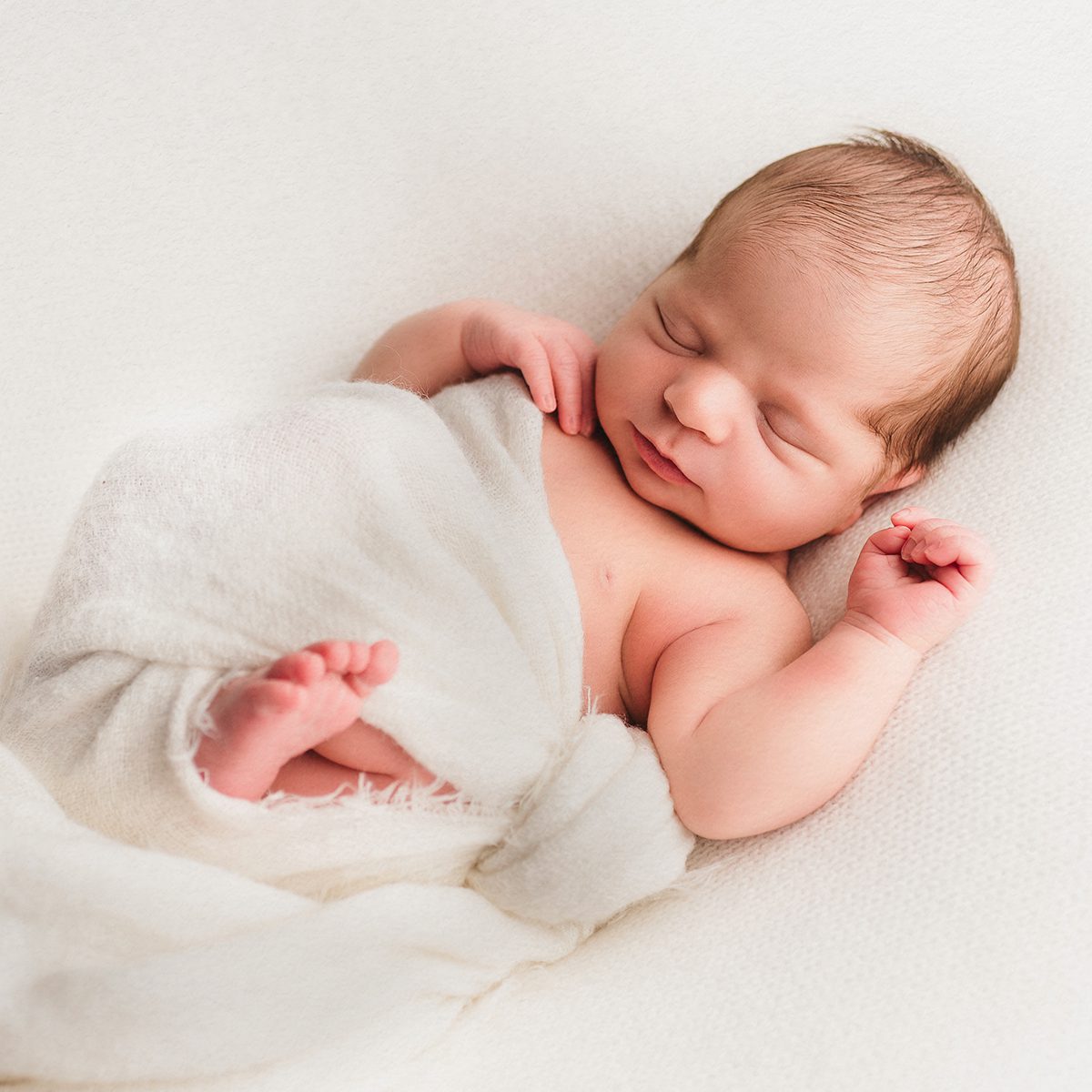 first year package 1 newborn image Sleeping newborn baby wrapped in soft neutral fabric, posed on a cream backdrop during a minimalist Connecticut studio newborn session.