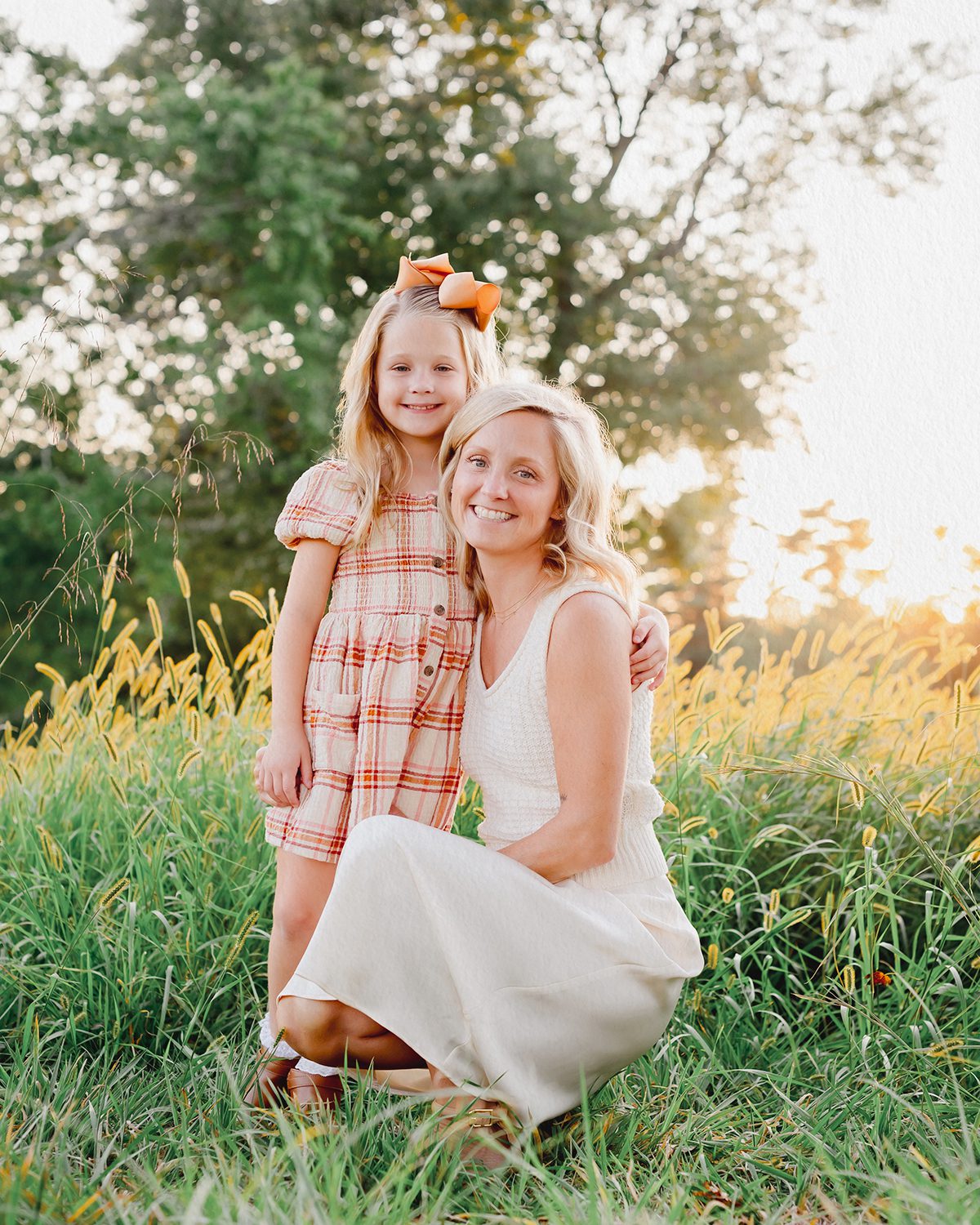 A mother and daughter posing for a Connecticut photographer in an open field with tall grasses and golden light.