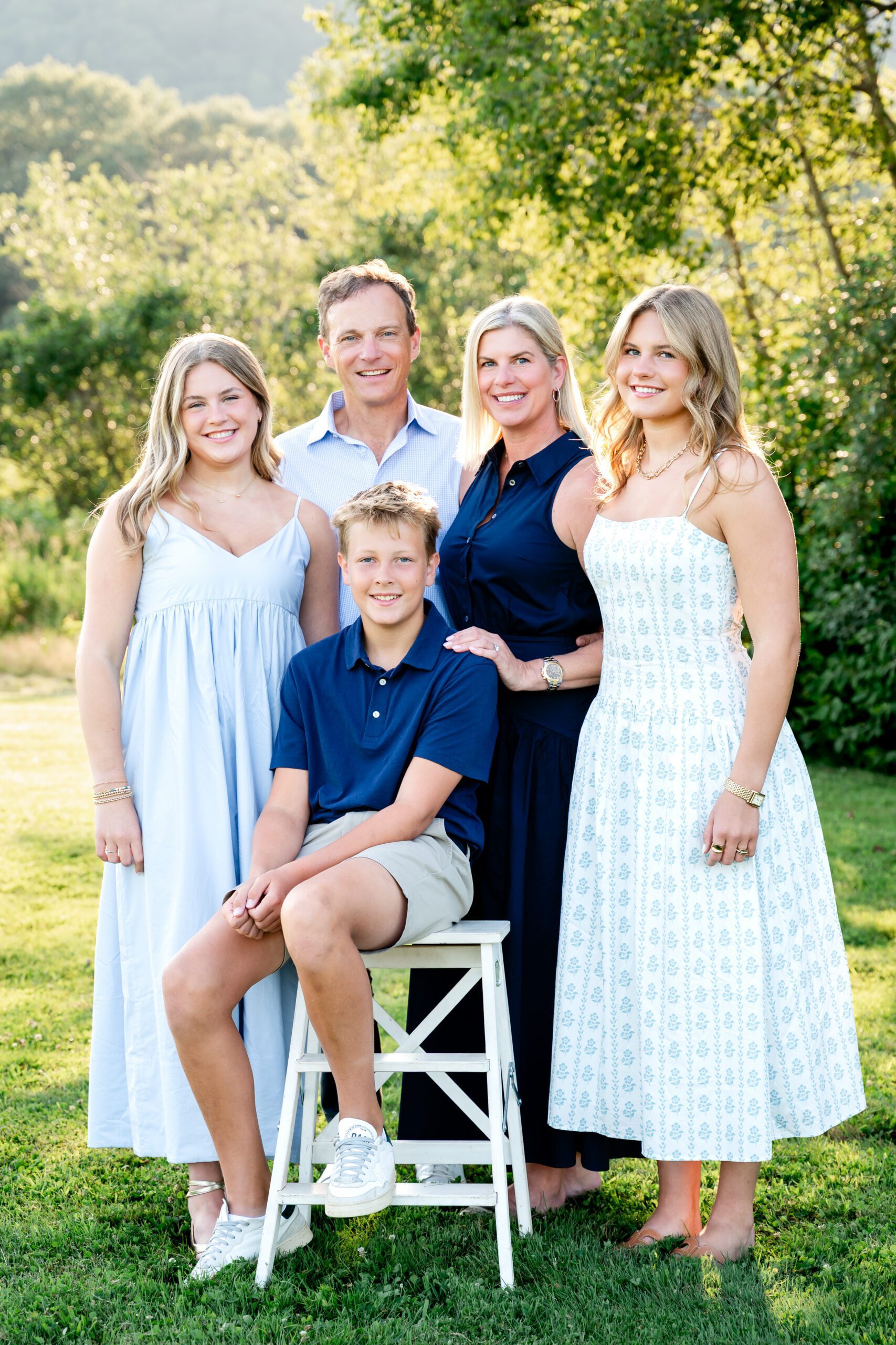 A family, posed in an open field, wearing varying shades of blue, during a Simsbury photography session with Kelli Dease.