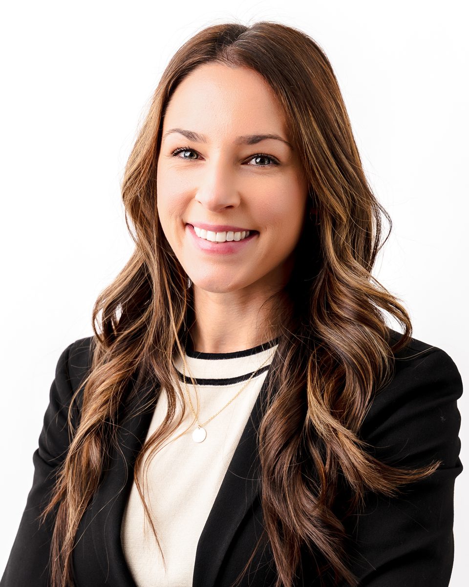 Professional headshot — woman in black blazer, close crop Woman with long wavy brown hair smiling in a black blazer during a professional headshot session at Kelli Dease Photography in Farmington, Connecticut