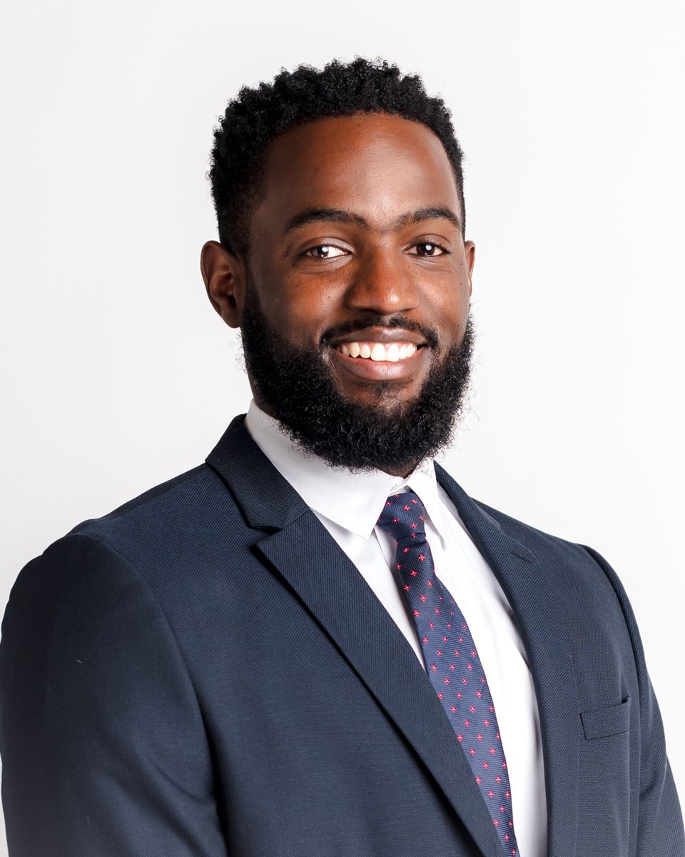 Man in a dark navy suit and tie smiling during a professional headshot session at a Connecticut photography studio
