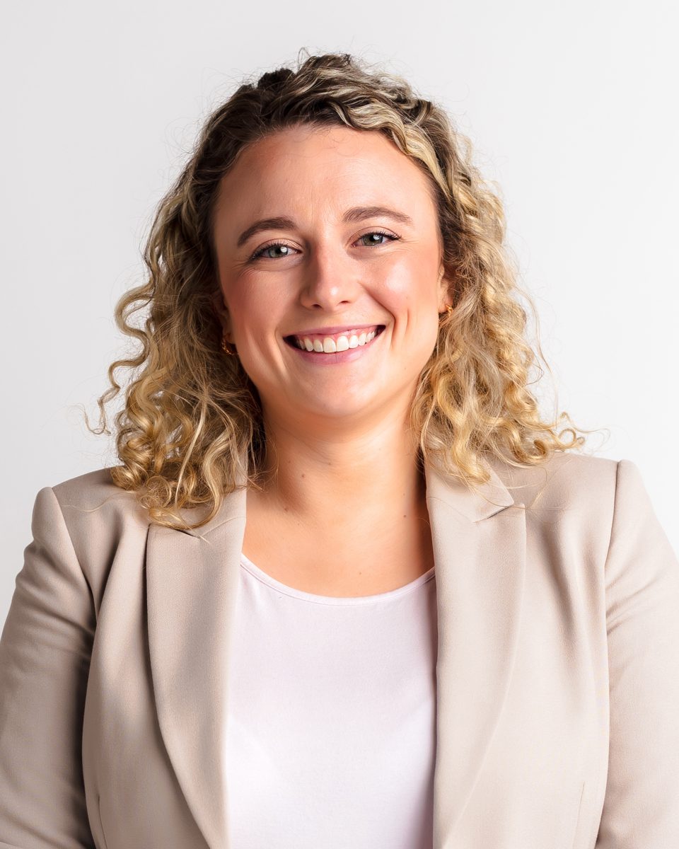 Woman with curly blonde hair in a beige blazer smiling during a professional headshot session at Kelli Dease Photography, Farmington CT