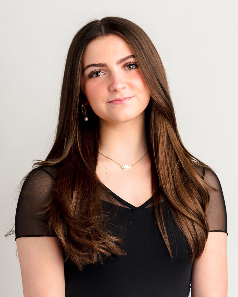 Young woman with long dark brown hair in a black top smiling during a professional headshot session at Kelli Dease Photography in Farmington, Connecticut
