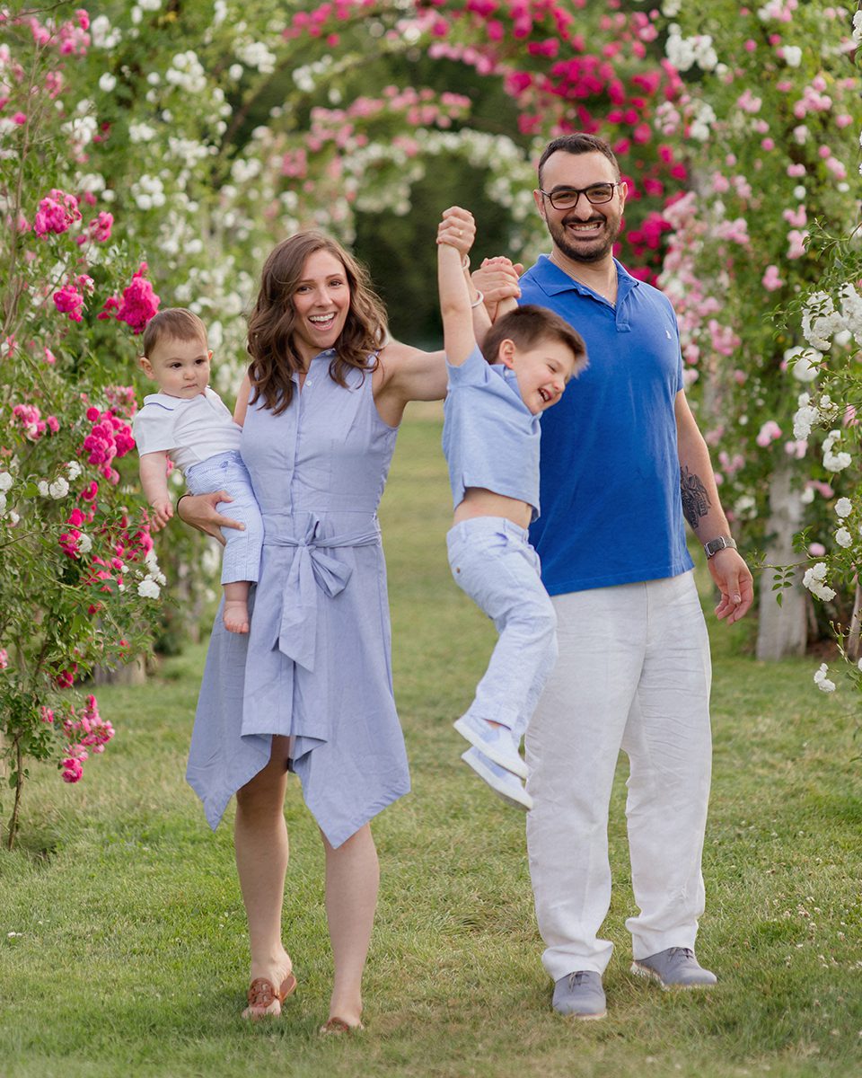 Family of four laughing together by the rose garden during a family photo session at Elizabeth Park in West Hartford