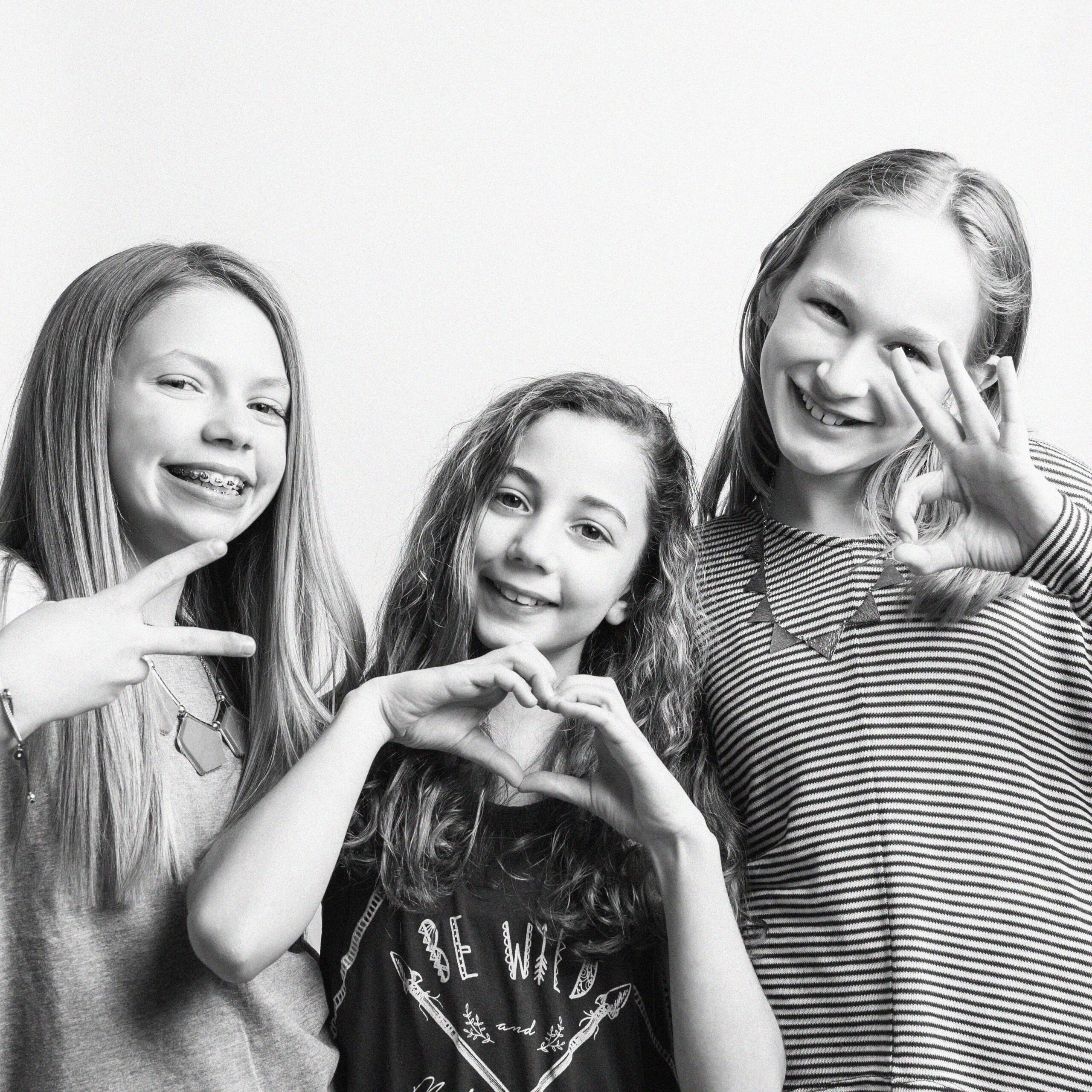 KDP_7094 BW SQ_WEB Three preteen girls laughing and making heart and peace signs in black and white photo during birthday session at Kelli Dease Photography, Farmington CT