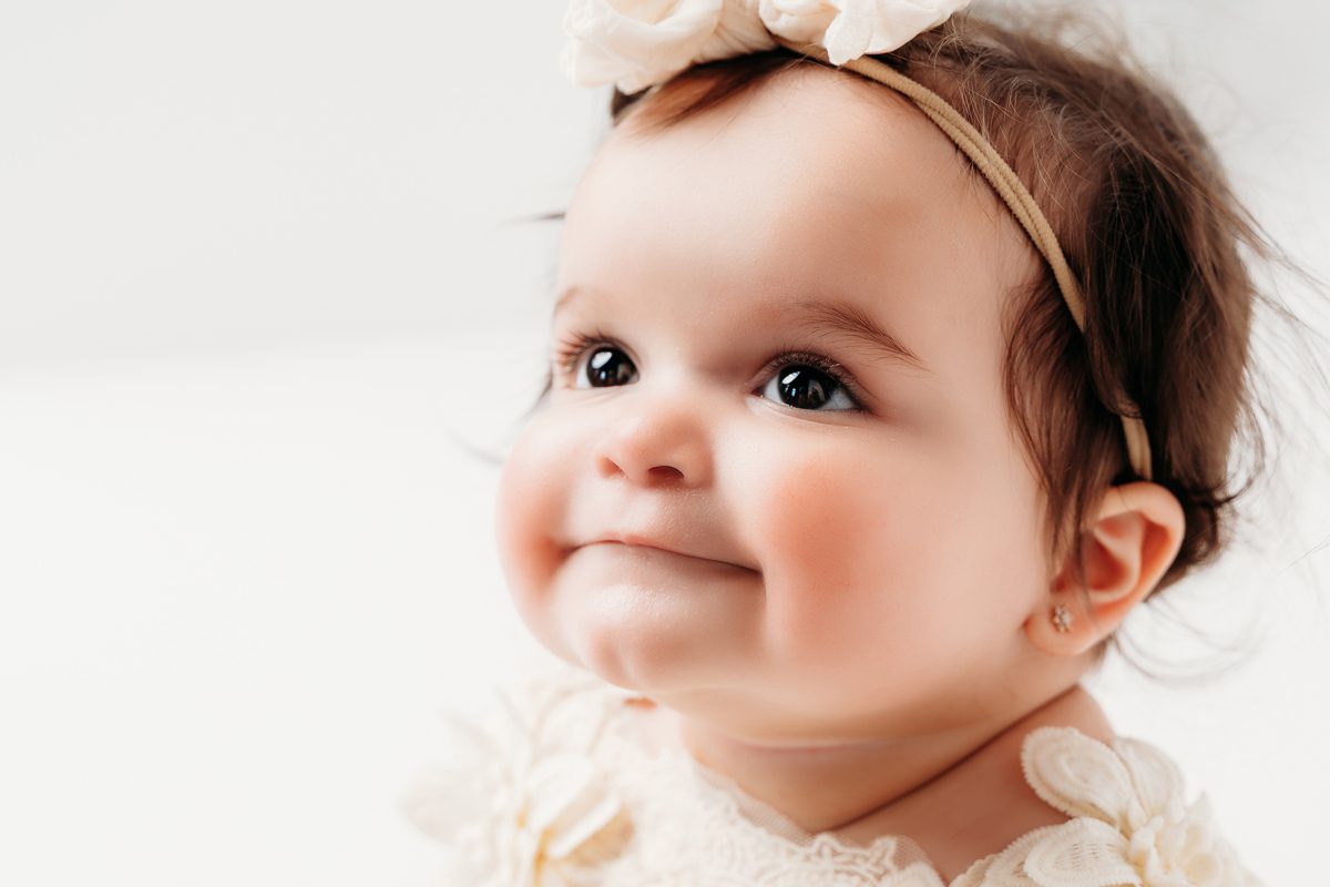 Baby girl laughing and looking to the side during her first birthday portrait session at Kelli Dease Photography in Connecticut