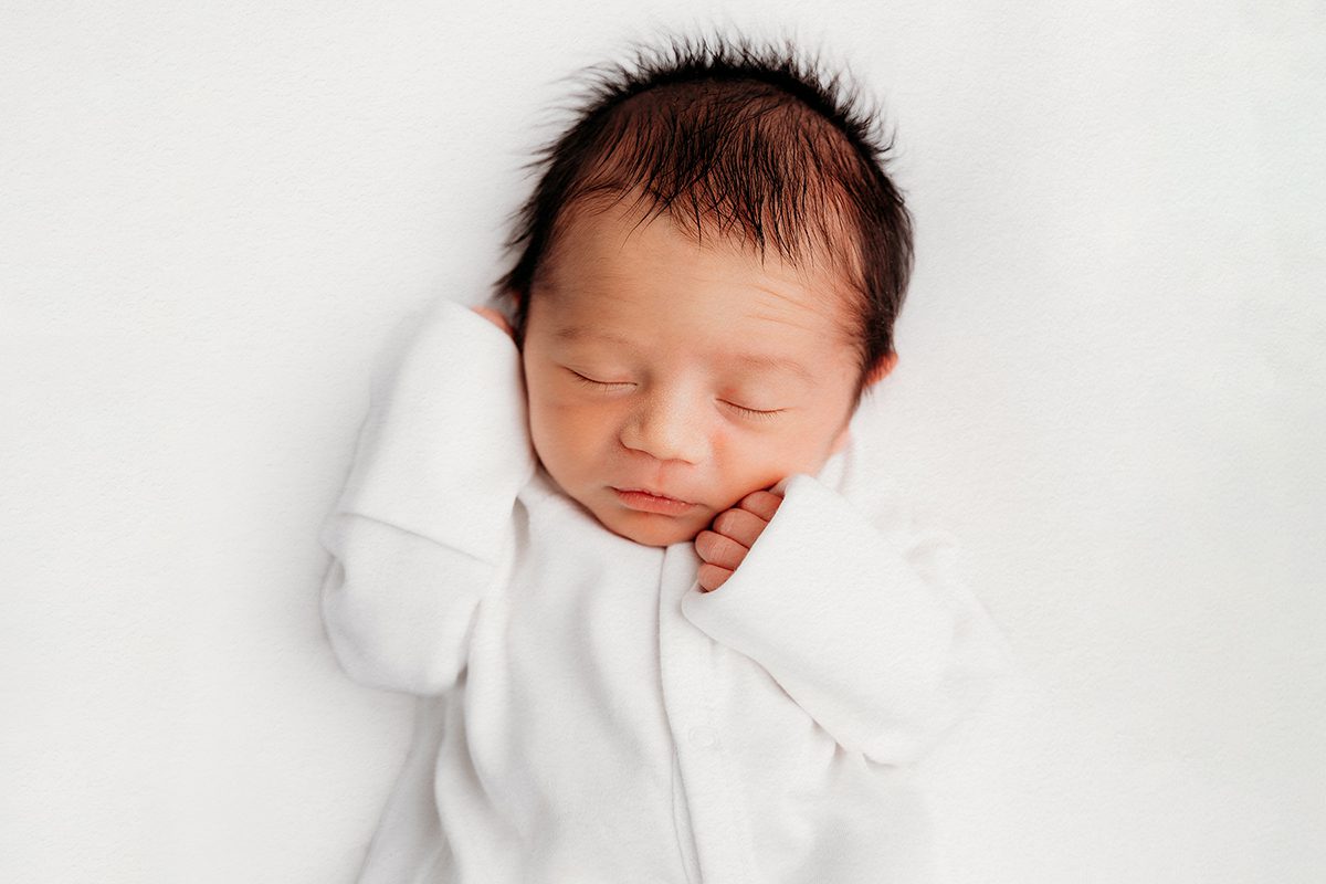 Newborn in a simple onesie on a light backdrop showing timeless, neutral editing, Kelli Dease Photography Connecticut