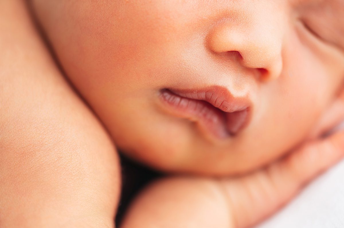 Close-up detail of a sleeping newborn's face, focused on soft lips and cheeks, photographed in a natural, timeless style by Farmington, CT newborn photographer Kelli Dease