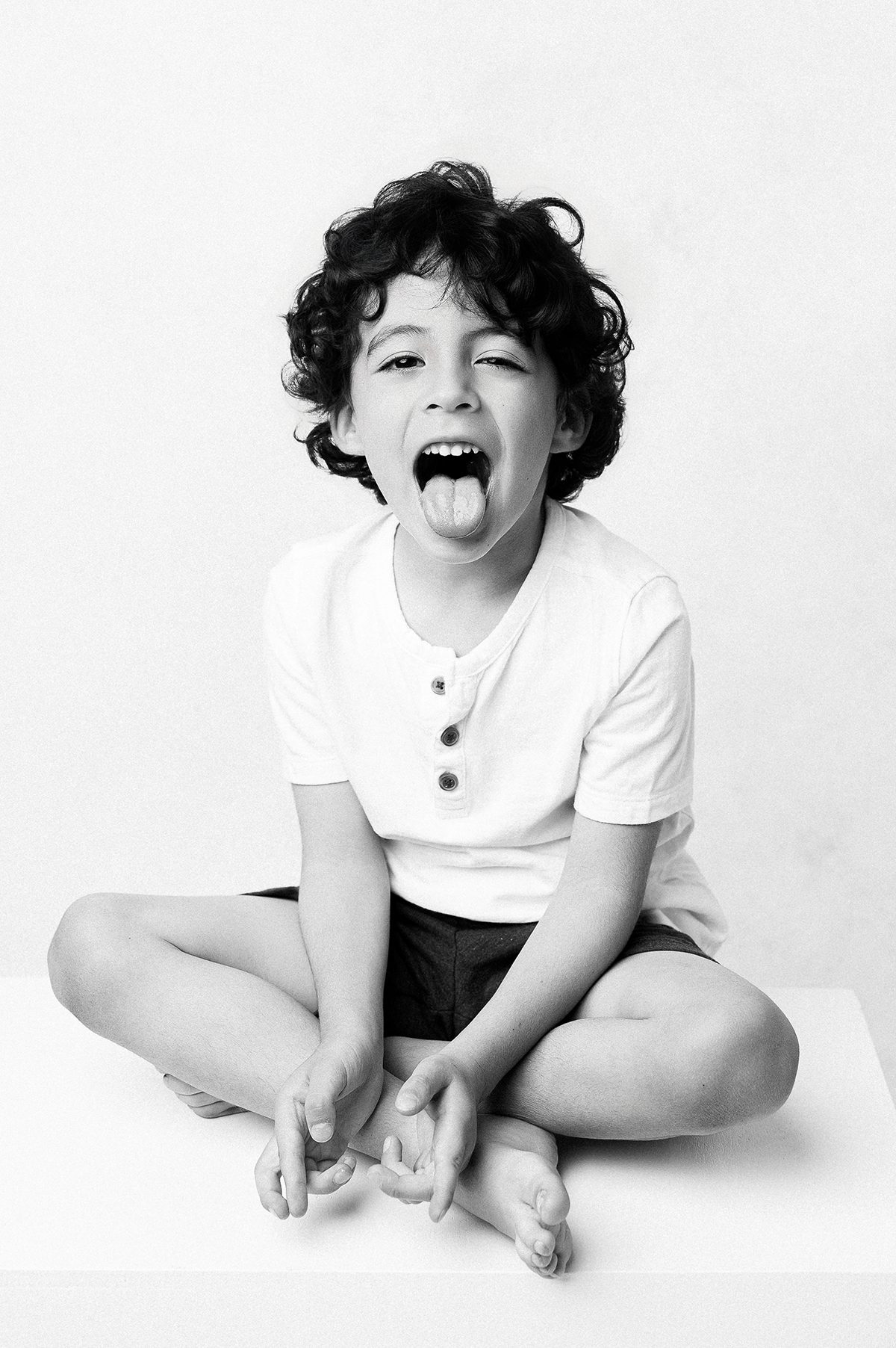 Young boy seated cross legged making a playful expression, Kelli Dease Photography Farmington CT
