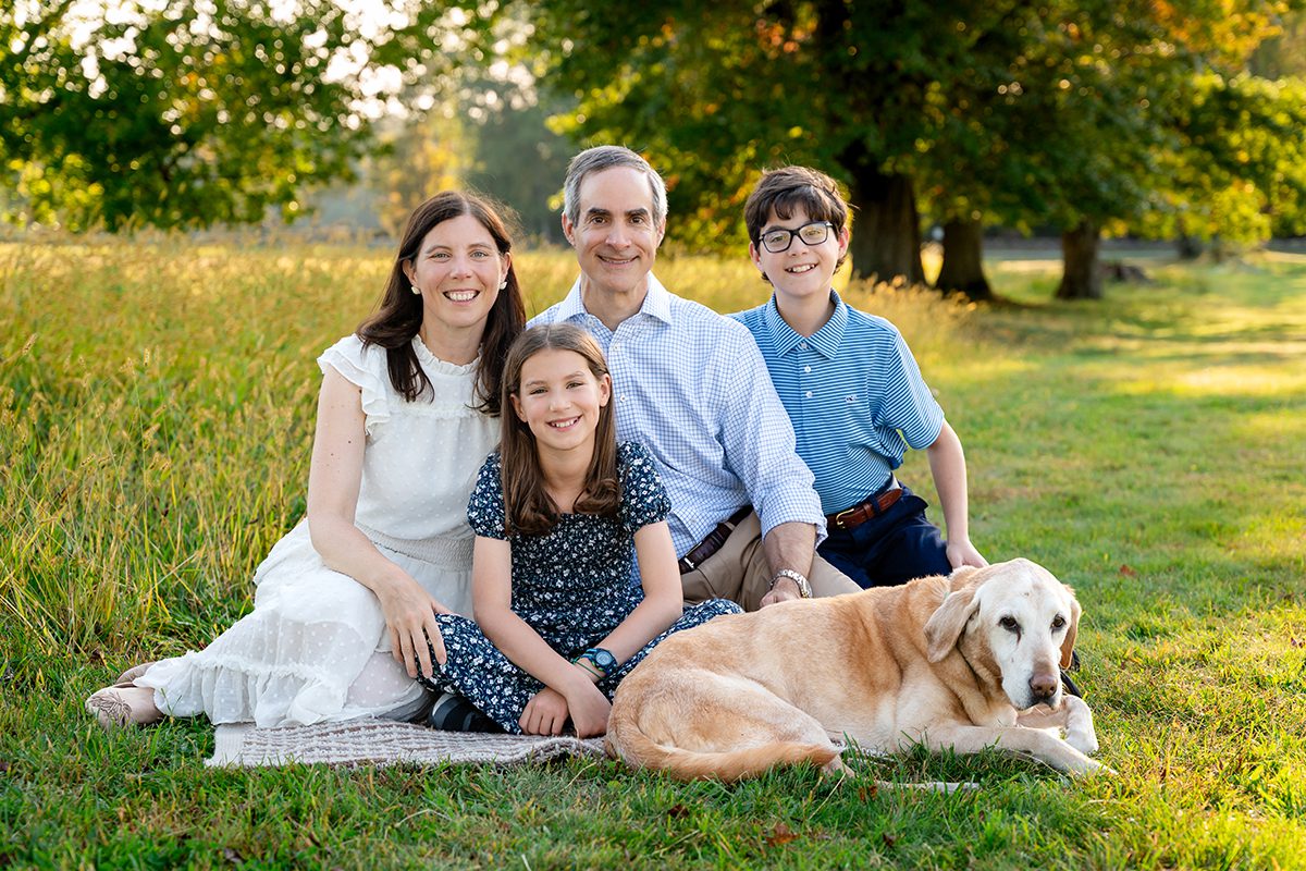 Family of four sitting on a blanket with their yellow Labrador during an outdoor Connecticut family session on a fall evening